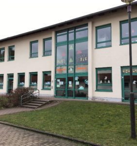 Grundschule Franzberg. Helles Gebäude mit grünen Fenstern.