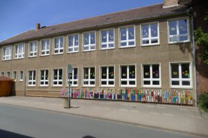 Grundschule Udersleben. Alteres, zweistückiges, braunes Gebäude mit bunten Bemalungen