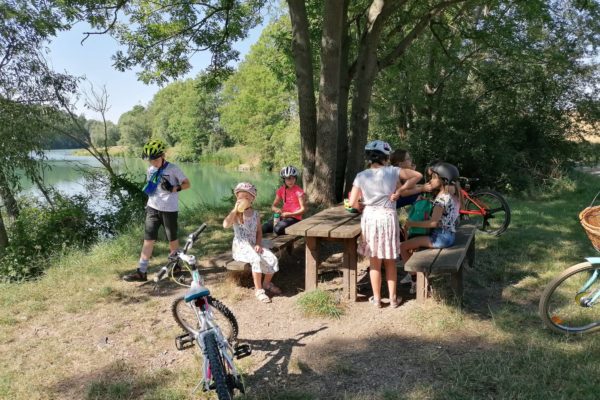 Kinder mit Fahrradhelmen machen Pause auf einer Sitzgruppe