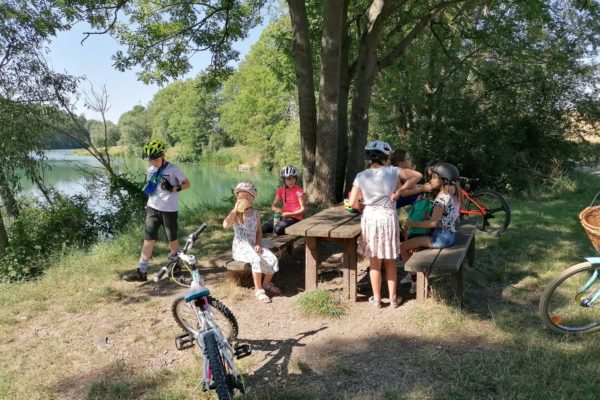 Kinder mit Fahrradhelmen machen Pause auf einer Sitzgruppe